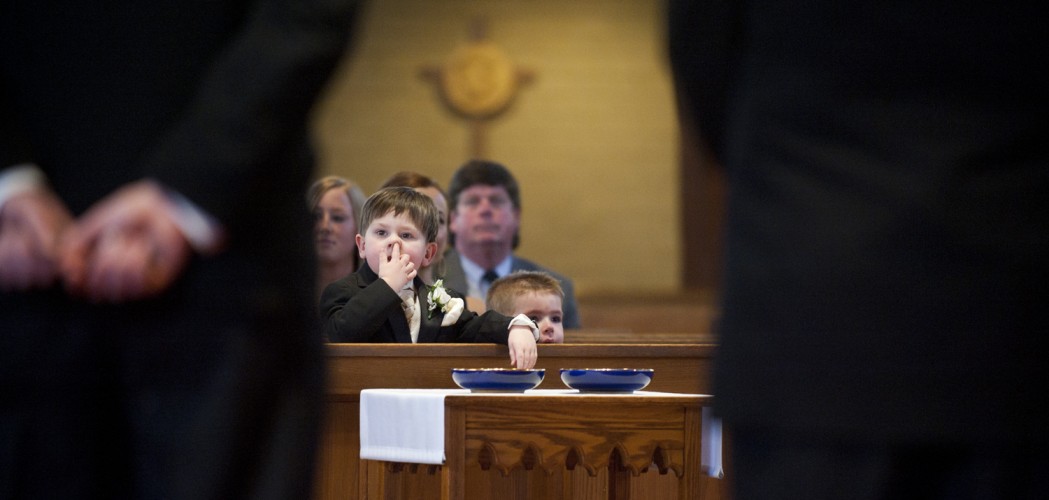 A ring bearer picks his nose at a wedding